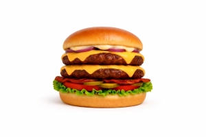 Dubbele 100% rundvlees burger (100 gr.) op een luxe broodje met twee plakjes cheddar, gebakken bacon(kip), gebakken ui, sla, tomaat, augurk en signature burgersaus.